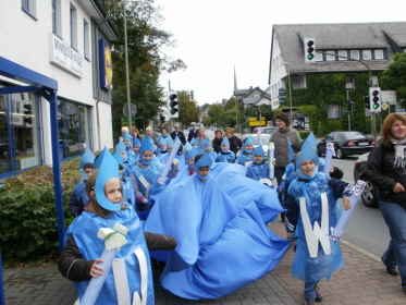 Als Wassertropfen verkleidete Kinder ziehen zum Rathausplatz.