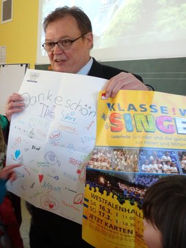 Sparkassenfilialleiter Püttmann umringt von Kindern des Projektes, die ihm die Geschenke überreicht haben