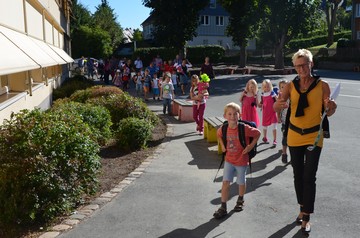 Foto der Klassenlehrerin mit den Kindern der neuen Klasse 1b auf dem Weg zum Klassenraum