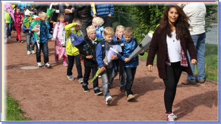 Foto der Klassenlehrerin mit den Kindern der neuen Klasse 1a auf dem Weg zum Klassenraum