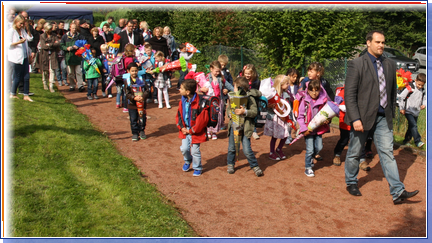 Foto des Klassenlehrers mit den Kindern der neuen Klasse 1b auf dem Weg zum Klassenraum